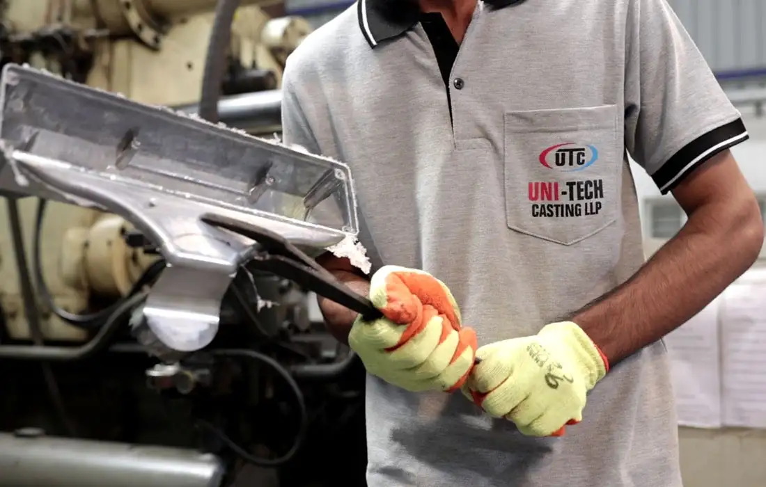 Worker wearing safety gloves inspecting metal component