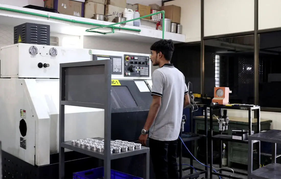 Operator performing CNC machining operation on precision metal components