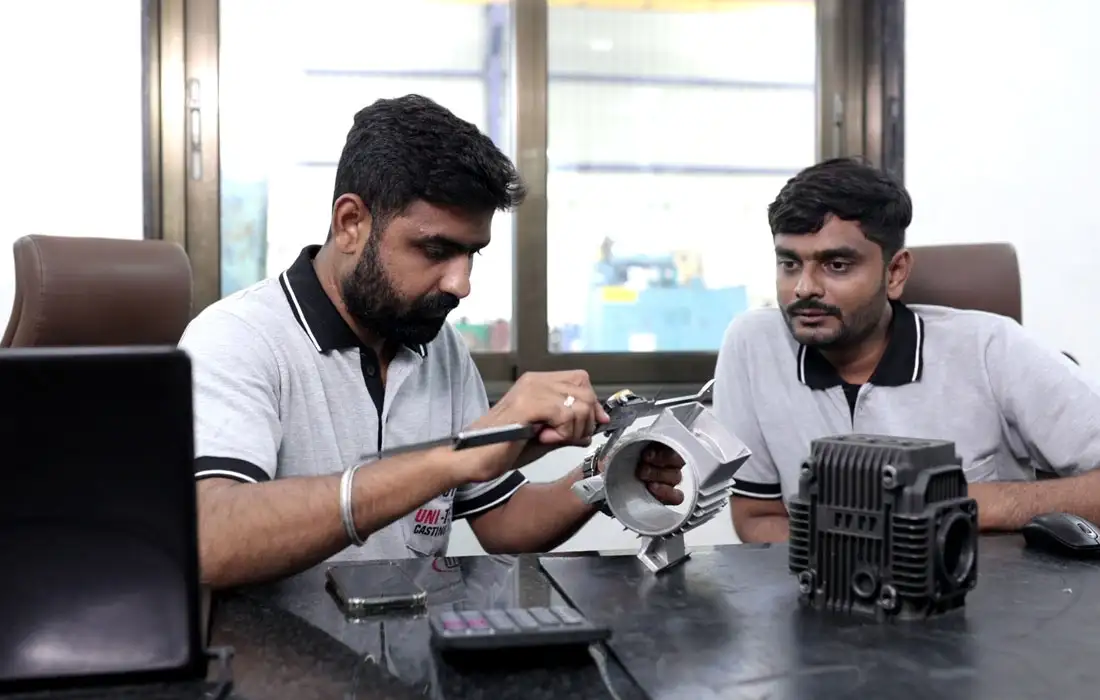 Engineers measuring precision-machined part and electric motor housing