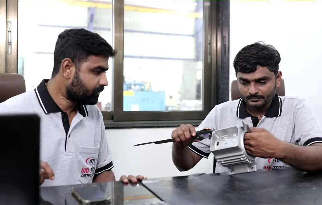 Engineers inspecting machined component and reviewing measurements