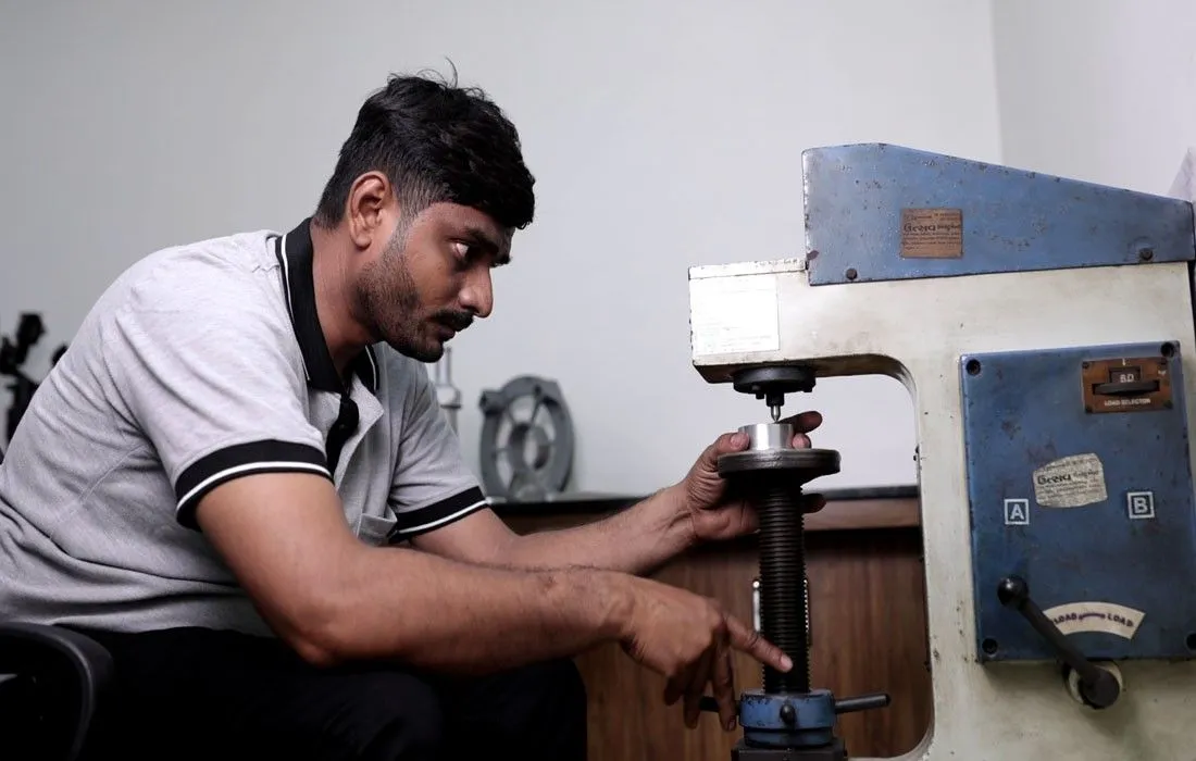 Technician operating precision drilling machine on metal component